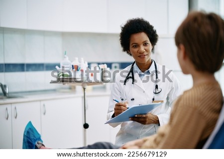 African American pediatrician communicating with a kid during medical appointment at doctor's office. Royalty-Free Stock Photo #2256679129