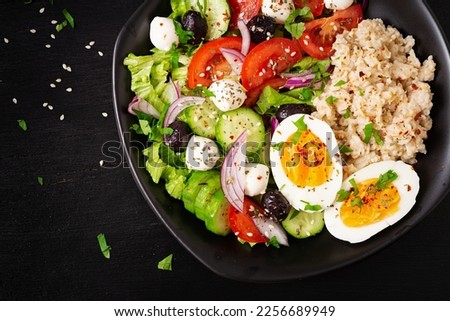 Healthy breakfast. Greek inspired savory oatmeal with fresh cucumber, tomatoes, olives, lettuce, mozzarella cheese and boiled egg. Top view