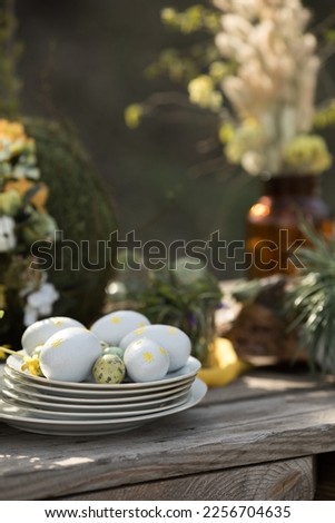 Easter eggs on a white plate on an outdoor dining table near the house