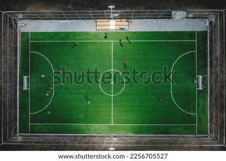 Aerial photo of a small football pitch with lights on with some movements of young players Royalty-Free Stock Photo #2256705527