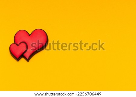 Two red hearts on a yellow background with copy space. Place for text. Postcard for congratulations. Valentine's Day.
