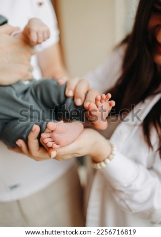 Close - up look light picture of a loving couple in white clothes  holding their newborn at home and enjoying their time together with a view on a newborn feet of a cute little baby boy