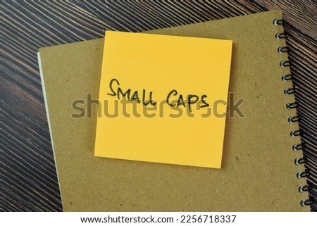 Concept of Small Caps write on sticky notes isolated on Wooden Table.