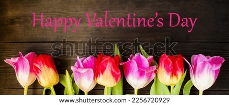 Festive card for Valentine's Day.  Beautiful flowers tulips and the inscription Happy Valentine's Day on a wooden background.  Concept theme of love and friendship.  Flat lay top view.