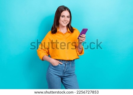 Photo of positive cheerful nice woman straight hairdo wear yellow shirt hold phone hand in pocket isolated on teal color background