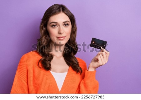 Photo of young confident banker wear orange stylish cardigan hold black premium debit card shopping choice isolated on violet color background