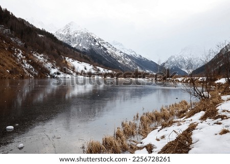 winter mountain lake in snow, in background of mountain, landscape pond with ice on water.