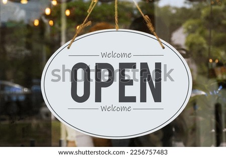 Hanging sign with message Welcome OPEN on glass door at coffee shop