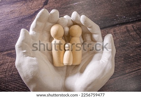 Close up of young women holding people shape male and female doll wooden peg dolls, family day, warmth, happiness, life insurance concept.
