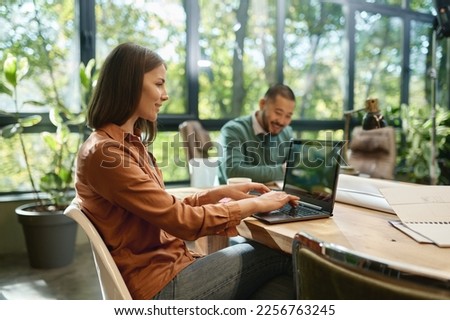 Smiling professional young businesswoman using laptop in coworking space