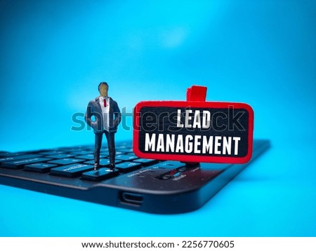 Miniature people and keyboard with the word LEAD MANAGEMENT on blue background. Business concept.