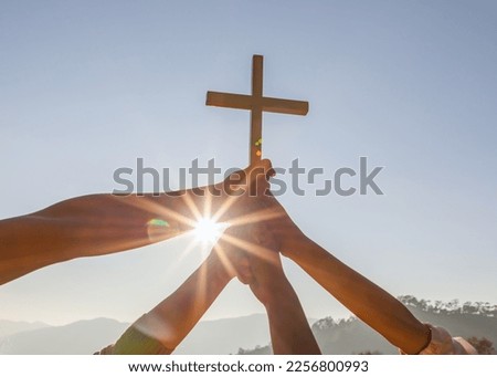 Silhouette family hands praying and holding Christian cross for worshipping God on mountain at sunrise background. Christian, Christianity, Religion copy space background. Easter Sunday concept: