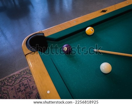 Clean pool table with a few cue balls, 4 ball, 9 ball, and pool cue stick scattered on the table in a modern game room, medium horizontal shot Royalty-Free Stock Photo #2256818925