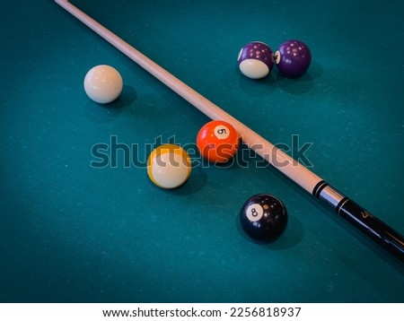 Clean pool table with a few cue balls and pool cue stick scattered on the table in a modern game room, close-up horizontal shot Royalty-Free Stock Photo #2256818937