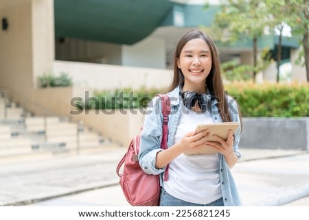 Beautiful student asian woman with backpack and books outdoor. Smile girl happy carrying a lot of book in college campus. Portrait female on international University. Education, study, school

