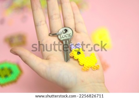 Girl is making educkling keychain at home. DIY and home business concept.  duckling keychain gift for Easter.  Plastic thermomosaic handmade, modern hobby for children.