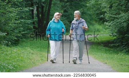 Elder family hikers pair fun stroll. Two happy old sportsman enjoy romantic date. Old sporty couple nordic walk poles green nature forest park. Elderly people fit workout. Old grandparents joy smile. Royalty-Free Stock Photo #2256830045