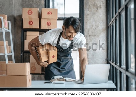 Handsome business sme owners in apron with delivery box package stock warehouse preparing after received online order from customer in social media in laptop, he is influencer. Royalty-Free Stock Photo #2256839607