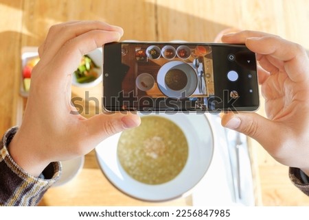 Male hands taking a pictures of their breakfast on mobile phone, top view.
