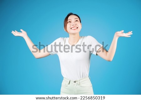 Portrait of young Asian woman standing on blue background
