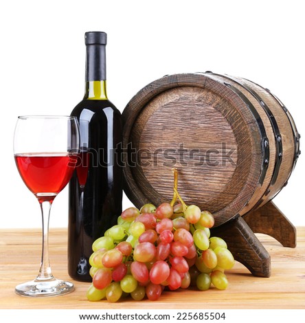 Wine in goblet and in bottle, grapes and barrel on wooden table on white background