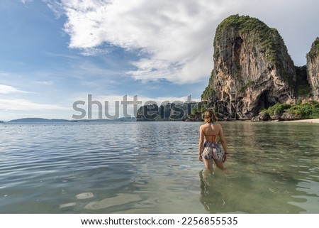 Traveler woman walking on the Phra nang Cave Beach with its turquoise waters enjoying the summer