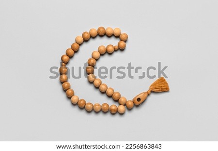 Prayer beads in shape of crescent for Ramadan on grey background Royalty-Free Stock Photo #2256863843