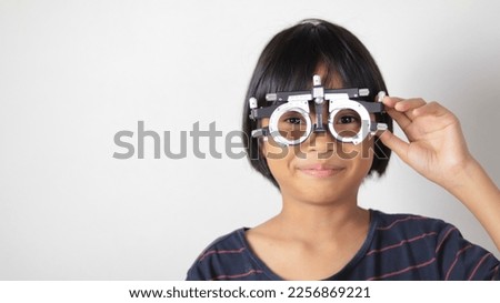 Elementary school girl wearing eyeglasses visual acuity test with test chart, eye test, Female patient checking eyesight in ophthalmology clinic, eye check Royalty-Free Stock Photo #2256869221