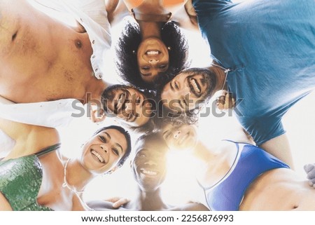 Six friends of diverse ethnicities, including an African, an Afro-American, and Caucasians, come together in a heartwarming embrace on the beach - joy and inclusivity of summertime fun Royalty-Free Stock Photo #2256876993