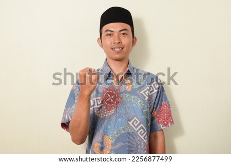 pose of a man celebrating and smiling while clenching his fists and raising both hands. illustration of Indonesian men being happy and excited. asian man in batik shirt on white background isolated
