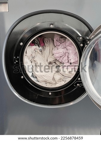 Washing clothes at a laundromat, the machine is loaded ready for use Royalty-Free Stock Photo #2256878459