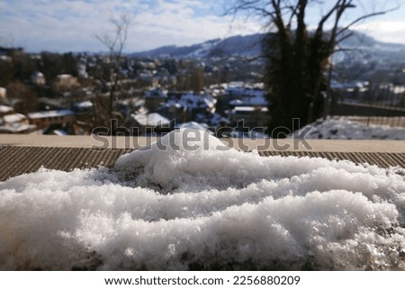 snow detail against blurred swiss city, winter concept