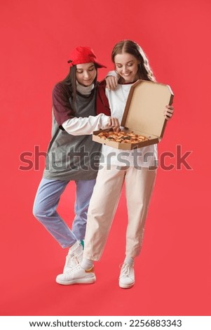 Young women with box of tasty pizza on red background