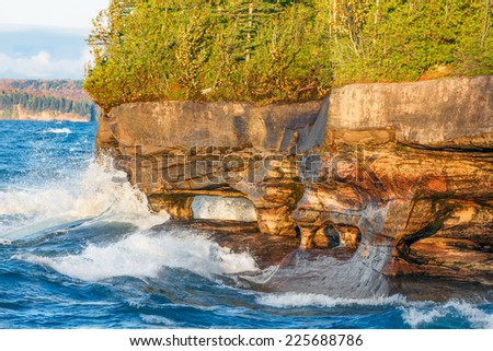Sea caves along the rocky, forested coastline  of Five Mile Point, near Christmas, Michigan, are pounded with waves near sunset.