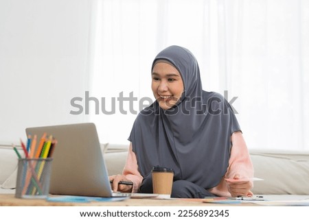 Asian young Muslim woman graphic designer wear hijab headscarf working and design color swatches samples with laptop computer in the workshop. Interior design and renovation concept
