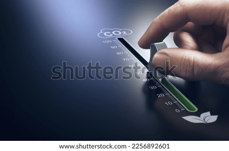Hand using a slider to reduce CO2 emissions. Carbon free energy. Concept of decarbonization. Royalty-Free Stock Photo #2256892601