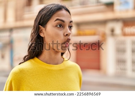 Young african american woman doing funny gesture with mouth at street