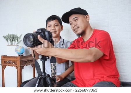 Father teaching cute little son to use digital camera for photography