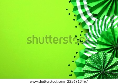 St. Patrick's Day banner template, cover, greeting card mockup. Folding paper fans decorations and clover leaves confetti on green background. 