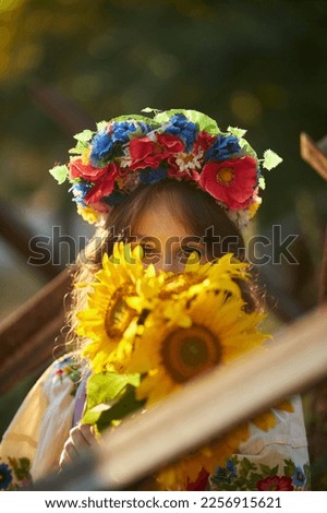 portrait of a Ukrainian woman in the Ukrainian national vyshyvanka dress with a bouquet of sunflowers against the background of anti-tank hedgehogs. close-up. War of Russia against Ukraine. 