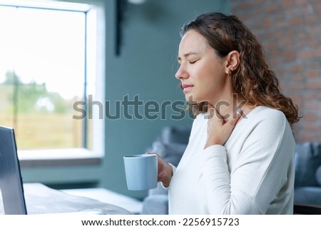 Young freelancer business woman with sore throat working with laptop pc in living room at home Royalty-Free Stock Photo #2256915723