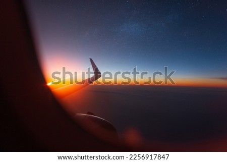 Amazing view from the porthole to the beautiful sunset, starry sky and clouds.Traveling by plane, concept. Airplane wing and turbine from the window Royalty-Free Stock Photo #2256917847