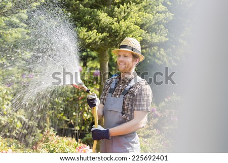 Happy man watering plants at garden