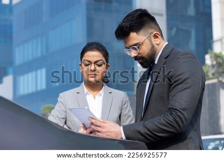 Business people using digital tablet outdoors.