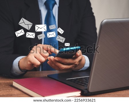 Businesswoman in a suit using a smartphone receives a new message with email icons while sitting at the table. Email notification on a mobile phone. Email marketing concept. Close-up photo