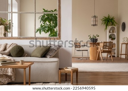 Interior design of cozy open space with modular sofa, green pillows, braided plaid, wooden coffee table, rattan armchair, round table, plants and personal accessories. Home decor. Template.  Royalty-Free Stock Photo #2256940595