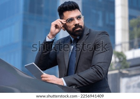 Portrait of Indian businessman with digital tablet outdoors in city.