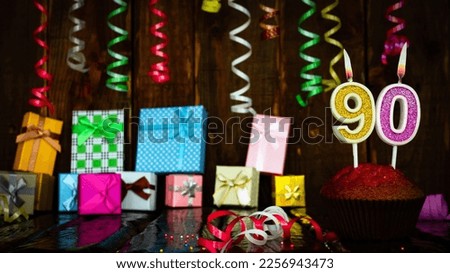Party birthday background with number  90. Beautiful background anniversary copy space with burning candles. Gift boxes with decorations.