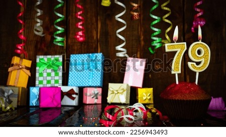 Party birthday background with number  79. Beautiful background anniversary copy space with burning candles. Gift boxes with decorations.