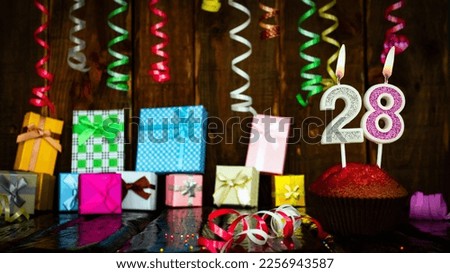 Party birthday background with number  28. Beautiful background anniversary copy space with burning candles. Gift boxes with decorations.